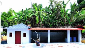 A small building with a red door and a covered area with a tiled floor. - Holy Trinity - Serviced Villa (Kundara)