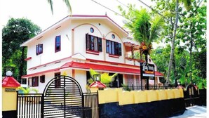 A two-story building with a red and white facade, a gated entrance, and a sign indicating it is a tourist attraction. - Holy Trinity - Serviced Villa (Kundara)