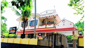 A two-story building with a red roof and a signboard that reads "Wow Trinity Tourist Home". - Holy Trinity - Serviced Villa (Kundara)