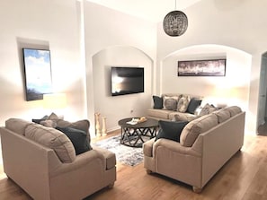 Ett vardagsrum med två soffor, ett soffbord, en tv och en kristallkrona.