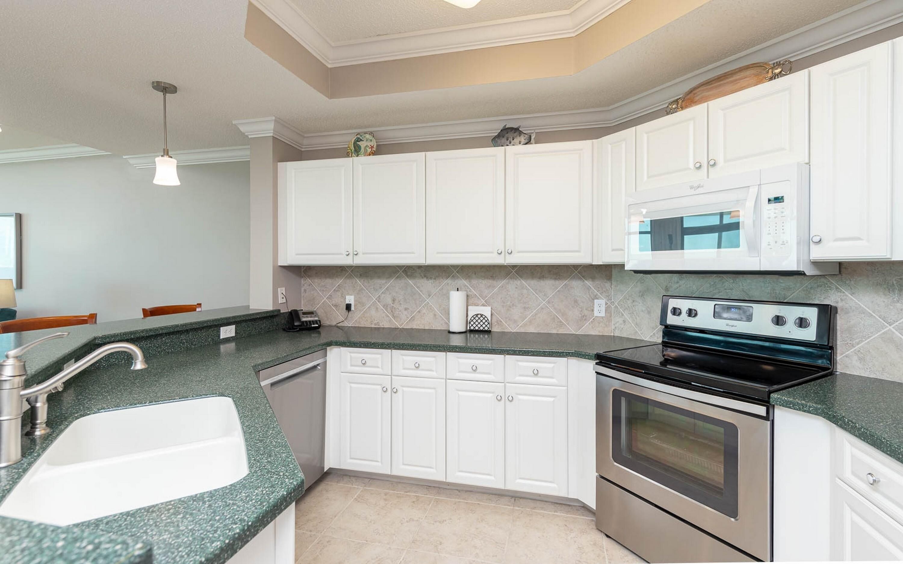 A kitchen with white cabinets, a granite countertop, a stainless steel oven, and a microwave.