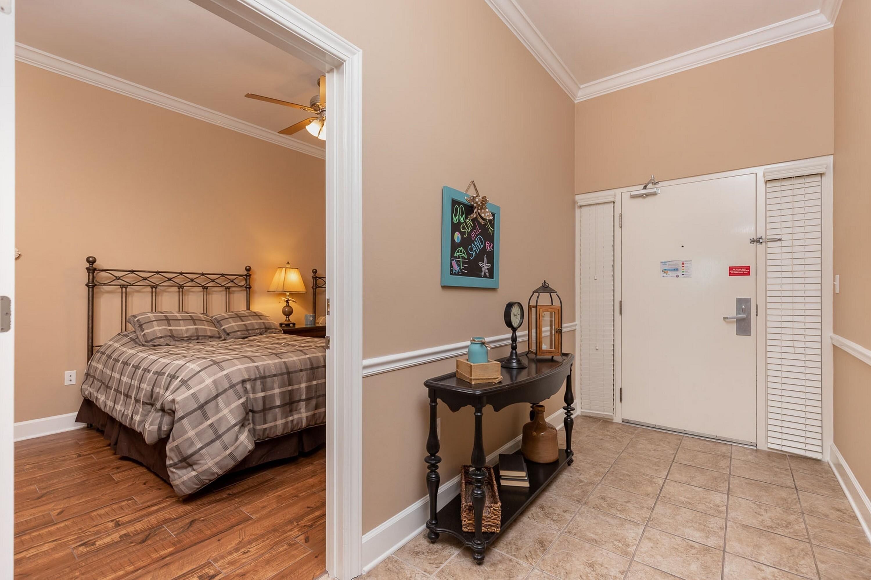 A bedroom with a bed, a nightstand, a wall clock, and a decorative wall hanging.