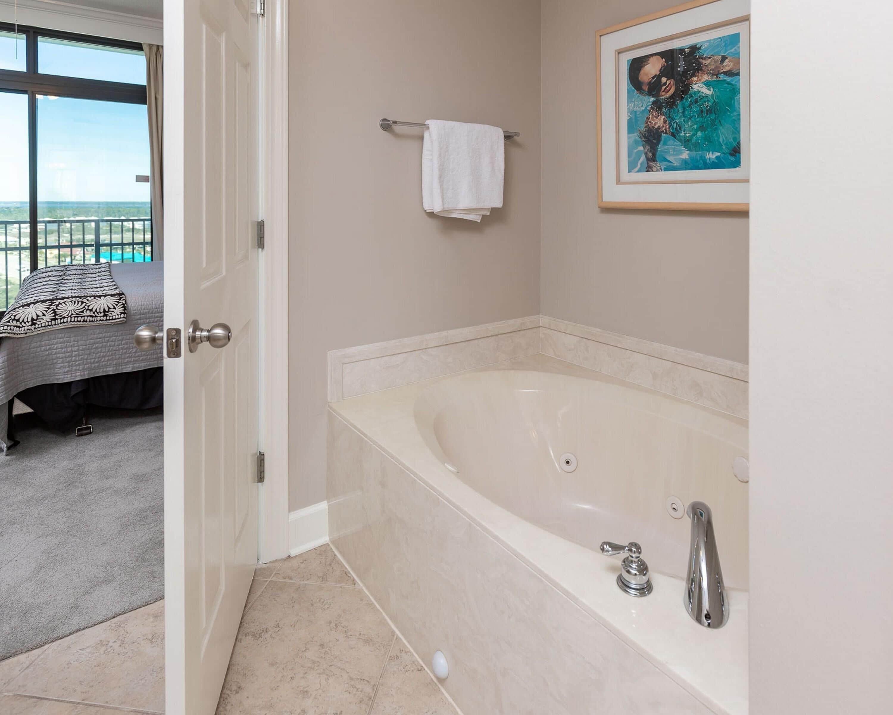 A bathroom with a large bathtub, a towel rack, and a framed picture on the wall.