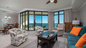 A spacious living room with a balcony, a dining area, and a view of the ocean.