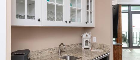 Una cocina con armarios blancos, encimera de granito y una pequeña decoración con forma de casa.