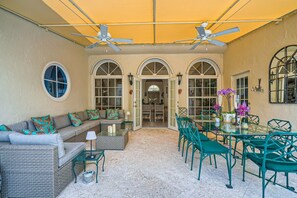 An outdoor patio with a sofa, chairs, a table, and ceiling fans.