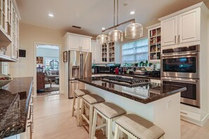 A modern kitchen with stainless steel appliances, a central island with bar stools, and pendant lighting.