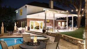 An outdoor patio area with a pool, fire pit, and seating.