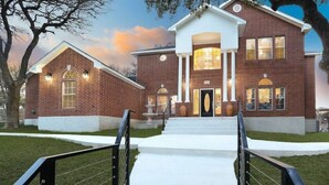 A two-story brick building with a central entrance, steps leading up to it, and a small porch area.