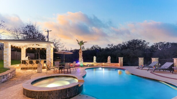 A swimming pool with a hot tub, outdoor bar, and lounge chairs.