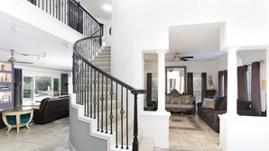 A spacious living area with a curved staircase, a fireplace, and a view of the outdoors.