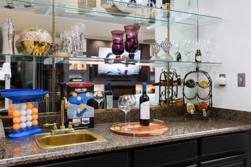 A kitchen with a granite countertop, a sink, a wine bottle, and a box of funnel cake mix.