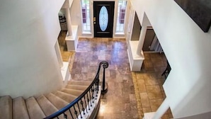 A grand staircase with a chandelier, a large window, and a door with a geometric design.