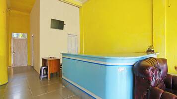 A reception area with a blue counter, a wooden desk, a leather chair, and a door.