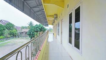 A corridor with a yellow exterior, metal railings, and large windows.