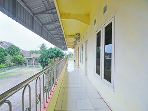 A corridor with a yellow exterior, metal railings, and large windows.