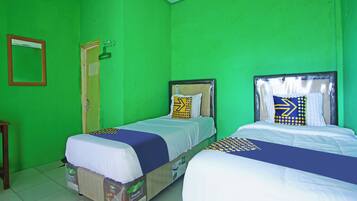 A room with two beds, green walls, and a wooden door.