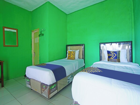 A room with two beds, green walls, and a wooden door.