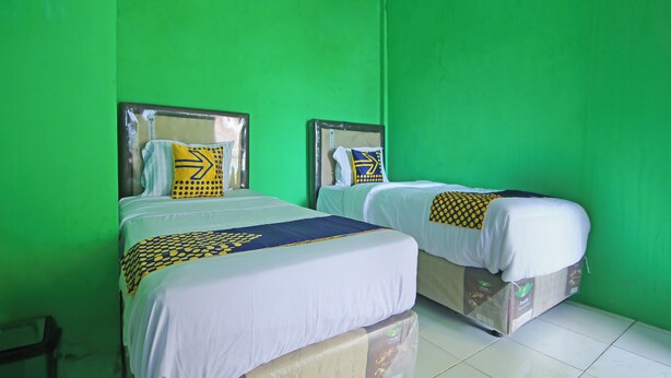 A room with two beds, green walls, and white bedding. - OYO 91111 Als Hotel (Lempuing)