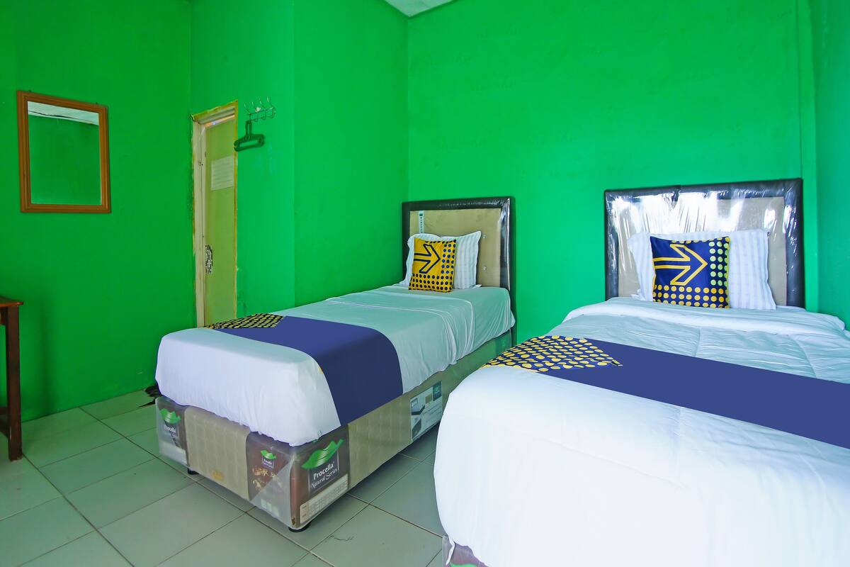 A room with two beds, green walls, and a wooden door.
