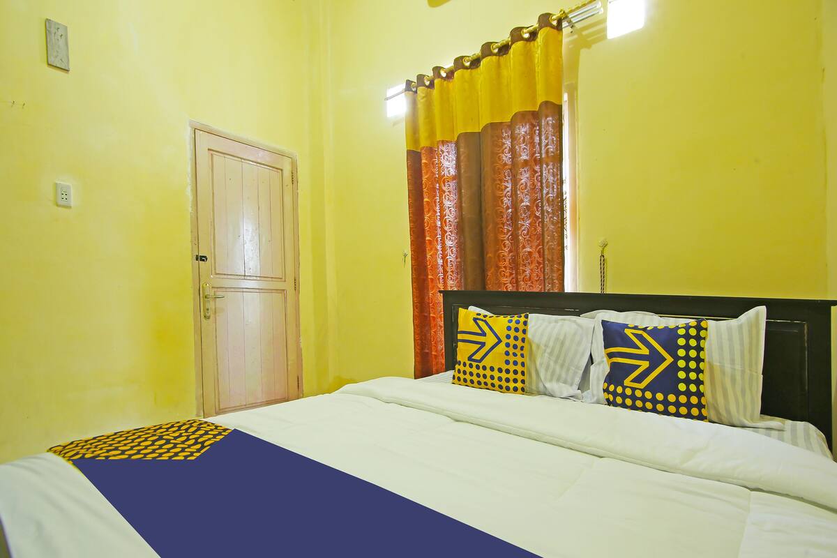 A hotel room with a bed, a door, and curtains.