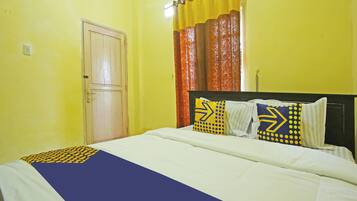 A hotel room with a bed, a door, and curtains.