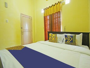 A hotel room with a bed, a door, and curtains.