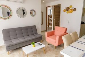 A living room with a grey sofa, a white coffee table, a pink armchair, and a beige sofa. There are three wall mirrors and a decorative wall piece. - Exclusive Apartament In El Rodadero -vita 945 No69 (Santa Marta)