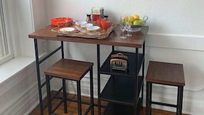 A corner dining area with a wooden table, two stools, a basket of fruit, and a hanging light fixture. - Lower East side NYC in Old Bisbee (Bisbee)