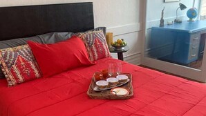 A bed with a red bedspread, a tray with breakfast items, and a nightstand with a lamp and a globe. - Lower East side NYC in Old Bisbee (Bisbee)