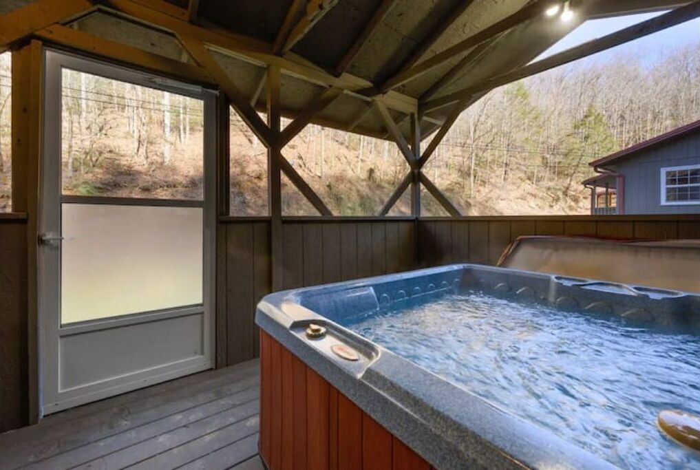 Ein Whirlpool unter einem Holzdach mit Blick auf eine bewaldete Landschaft.