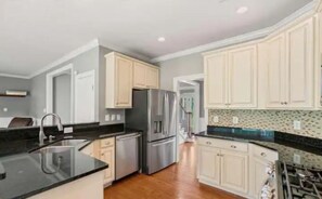 A modern kitchen with light-colored cabinets, stainless steel appliances, and a black countertop. - Large Modern House, Wine Country, Delaplane, VA (Delaplane,)