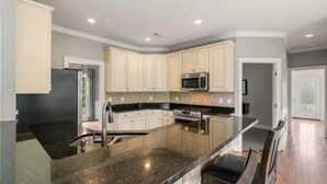 Una cocina moderna con una isla grande, electrodomésticos de acero inoxidable y armarios de color claro.