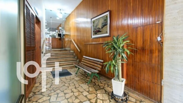 A hallway with wooden paneling, a staircase, a bench, and a potted plant. - Ap Copacabana 200m da praia - CP2 (Rio de Janeiro)