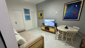 A room with a bed, a TV, a dining table, and chairs. - Ap Copacabana 200m da praia - CP2 (Rio de Janeiro)