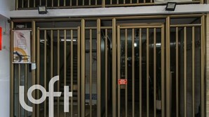 A metal gate with vertical bars and a logo on the left. - Ap Copacabana 200m da praia - CP2 (Rio de Janeiro)