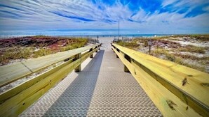 En träpromenad som leder till en strand med klar himmel.