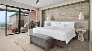 Un dormitorio moderno con una cama grande, un ventilador de techo y vista al océano.