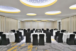A conference room with multiple tables, black chairs, and a patterned carpet.