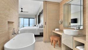 Un baño de hotel moderno con una bañera grande, un tocador con lavamanos y un espejo amplio.