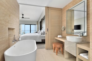 A modern hotel bathroom with a large bathtub, a vanity with a sink, and a large mirror.