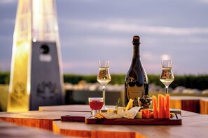 A table set with a bottle of champagne, two glasses of white wine, a bowl of red sauce, cheese, crackers, and olives. - The Westin Resort & Spa, Himalayas (Narendranagar)