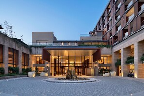 Ein modernes Hotel mit Innenhof, großen Fenstern und einem Wasserspiel.