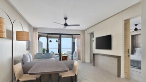 Una sala de estar moderna con comedor, ventilador de techo, televisor de pantalla plana y vistas al exterior.