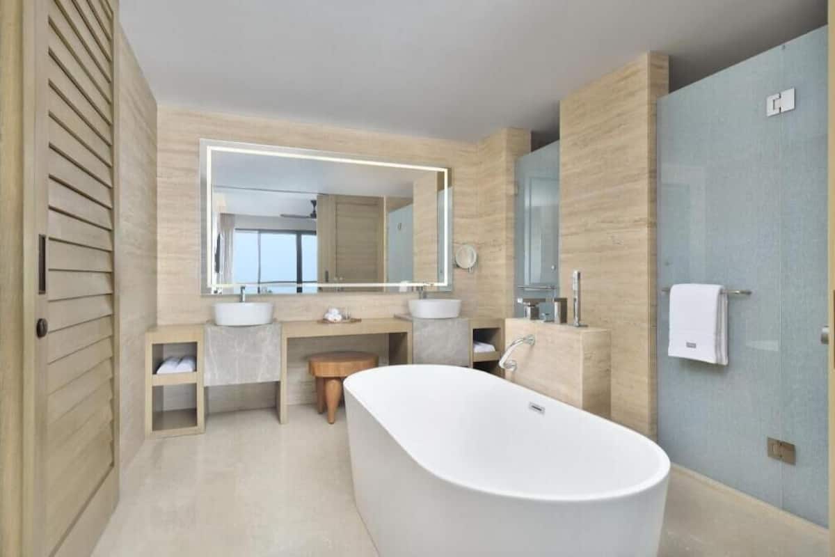 A modern bathroom with a freestanding bathtub, two sinks, and a large mirror.