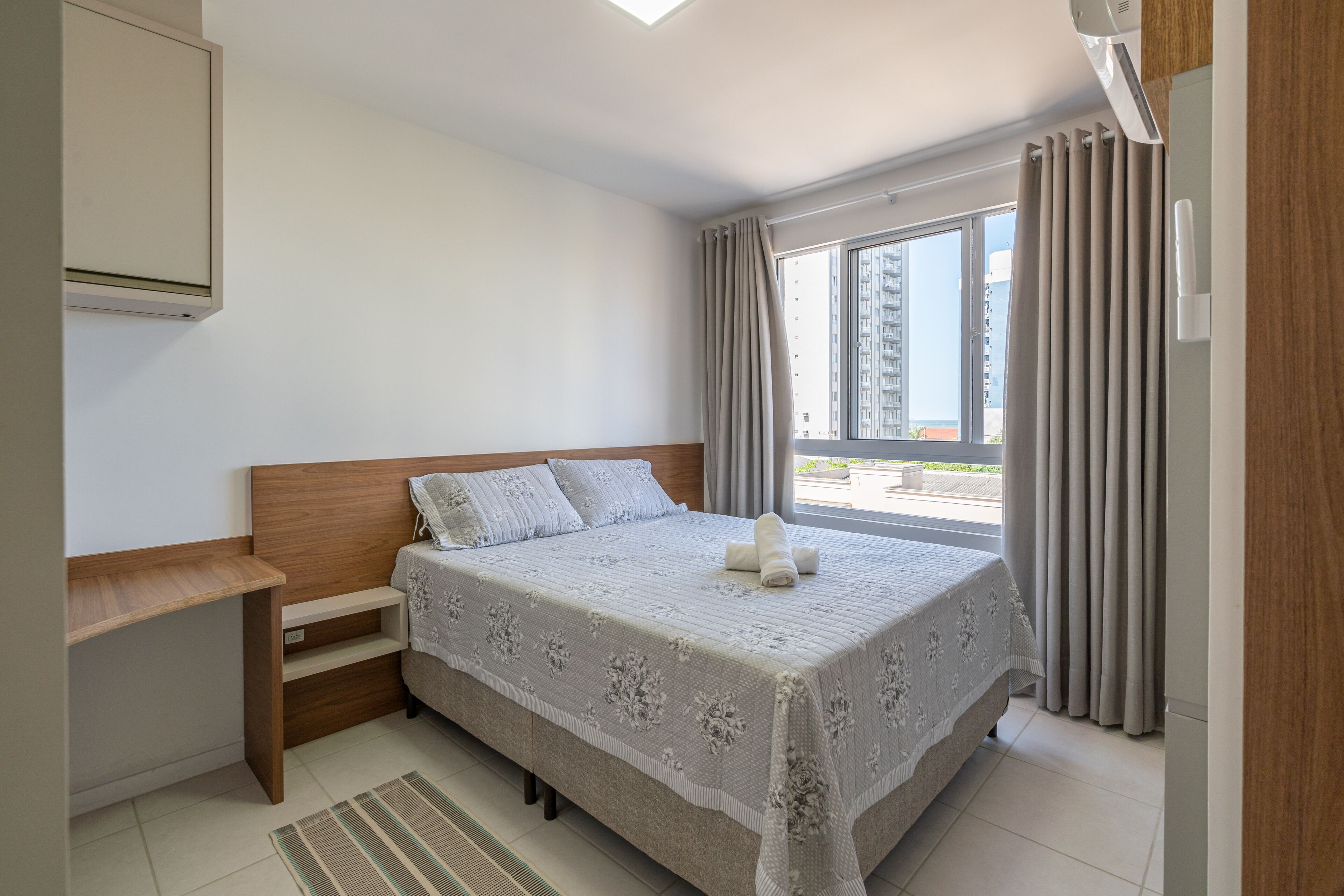 Ein Schlafzimmer mit Bett, Schreibtisch und einem Fenster mit Vorhängen.