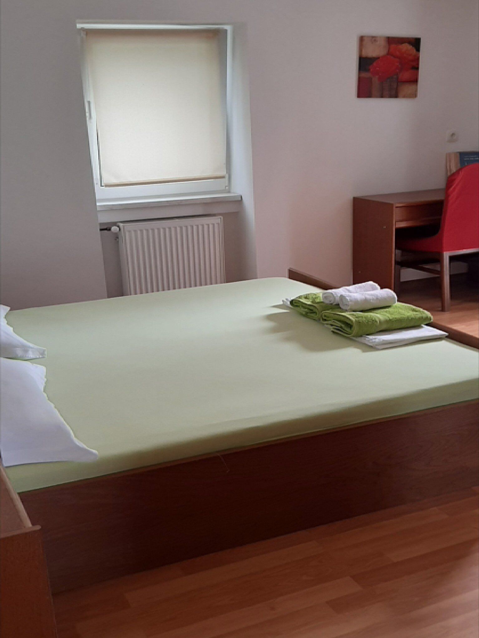 Une pièce comprenant un lit, un bureau, une chaise et un radiateur.