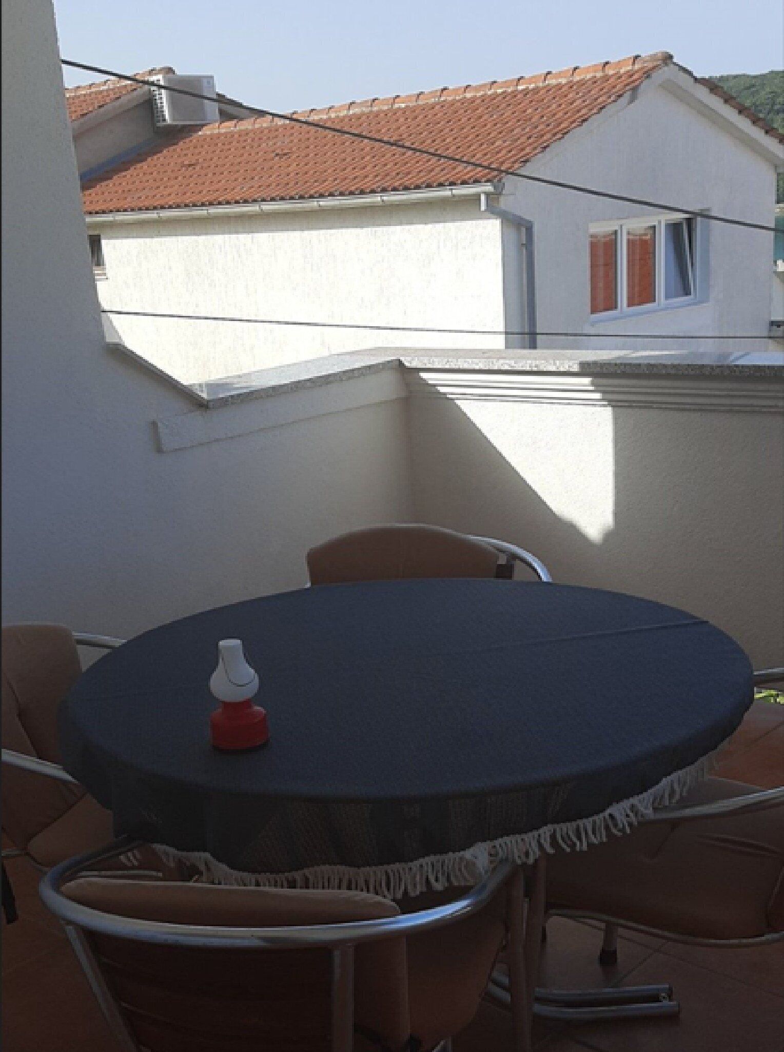 A round table with a dark tablecloth, surrounded by four chairs with a fringe detail.