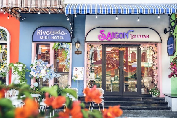 A hotel with a sign for 'Riverside Mini Hotel' and an adjacent ice cream shop named 'Saigon Ice Cream'. - Riverside Mini Hotel Grand World (Phu Quoc)