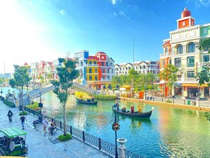 A canal with gondolas, a pedestrian bridge, and colorful buildings along the water's edge. - Riverside Mini Hotel Grand World (Phu Quoc)